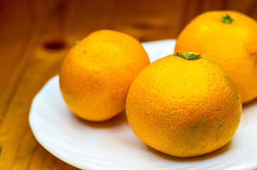 tangerines in white saucer on wooden table