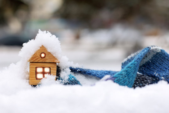 warm clothes for warming in winter/ small wooden house and blue scarf on the background of snow-covered landscape