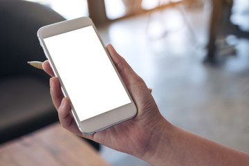 Mockup image of a hand holding white mobile phone with blank screen and a pen in office