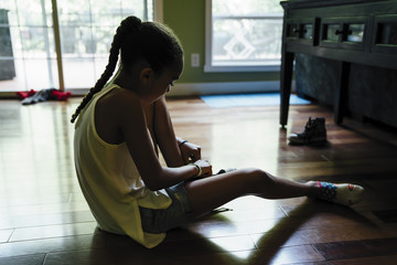Girl sitting on floor putting on shoes