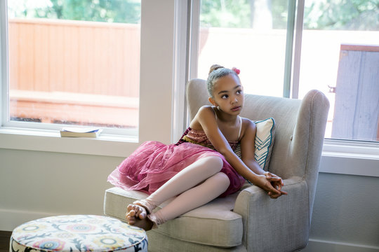 Sad girl in ballet outfit sitting in living room 