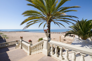Public access to sandy Voramar Beach, in Benicassim, Castellon, Valencia, Spain, Europe. Great palm tree, classic stairs with vases with flowers, blue clear sky and Mediterranean Sea. Horizontal 