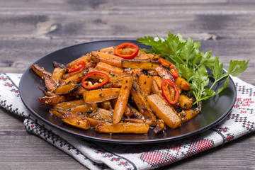 Healthy homemade roasted carrots ready to eat in black plate