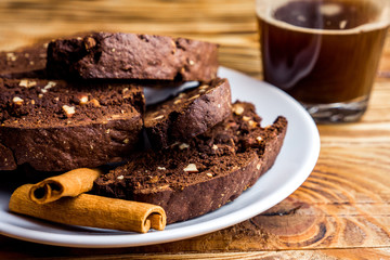 Homemade chocolate biscotti cookies with almonds on dark wooden background on white plate. Close up 