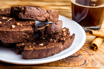 Homemade chocolate biscotti cookies with almonds on dark wooden background on white plate. Close up 