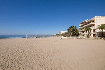 sandy and lonely Voramar Beach, in Benicassim, Castellon, Valencia, Spain, Europe. Buildings, blue clear sky and Mediterranean Sea. Horizontal
