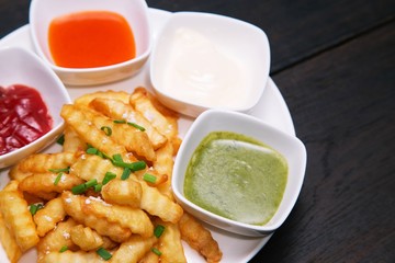 French fries with ketchup,chili sauce,mayonnaise,wasabi on wooden background, top view