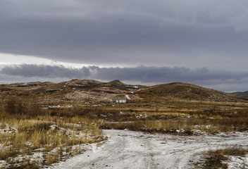 Dramatic dark winter steppe. Thaw. Ice road. City outskirts of the city of Ust-Kamenogorsk, Kazakhstan