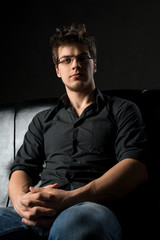 Young sexy man on leather sofa cropped portrait