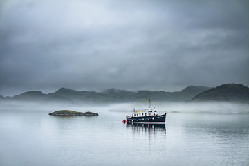 Alone boat driving through in the foggy sea in the scottish highlands © Lukassek