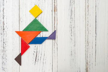 wooden tangram shaped like a man kicking his leg with copy space