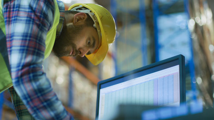 Male Inspector Wearing Hard Hat Fills in Spreadsheets on His Personal Computer. He's in Big...