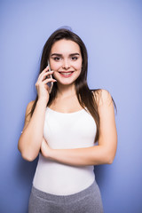 Beautiful young woman talking by mobile phone at curtains at home