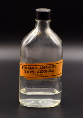 Ethanol Bottle on Seamless Black Background. 
