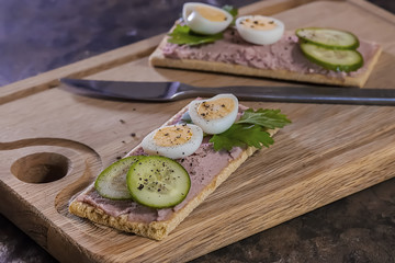 Fresh homemade meat pate on over crispbread on wooden board.