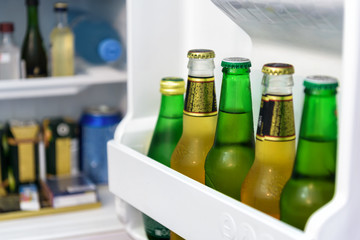 Mini fridge full of bottles in hotel room, the open door of refrigerator