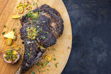 Australian barbecue dry aged wagyu tomahawk steak with fruit relish as close-up on old wooden board