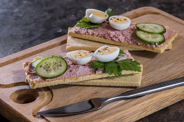 Fresh homemade meat pate on over crispbread on wooden board.