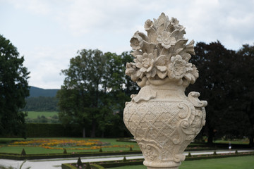 Fototapeta na wymiar Elaborately carved vase with flower with View of the Castle Gardens at Cesky Krumlov from the upper terrace.
