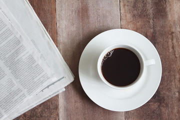 White coffee cup and news paper on wood table