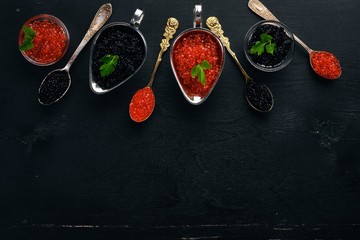 Spoon with black and red caviar on a wooden background. Top view. Free space for text.