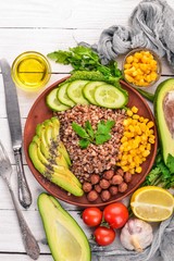Healthy food. Buckwheat, avocado, cucumber, corn and hazelnut. On a wooden background. Top view. Free space for your text.