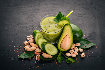 Smoothie with avocado and cucumber with flaxseed and nuts. On a wooden background. Top view. Free space for your text.