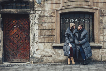Fototapeta na wymiar Classy groom and his gorgeous bride pose outside in winter coats