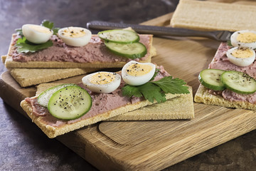 Fresh homemade meat pate on over crispbread on wooden board