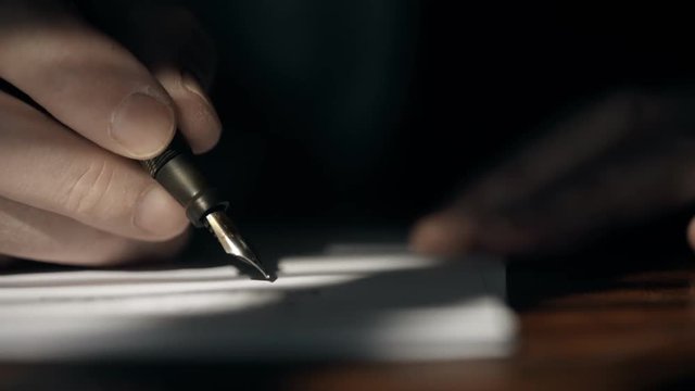 Super close footage of a Caucasian businessman in 1930 making entries into a business ledger or engaged in handwritten communication using a fountain pen.