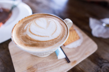 Cup of cappuccino coffee on the wooden table in the coffee shop