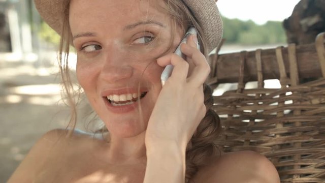 Young woman wearing hat using smartphone during summer. 