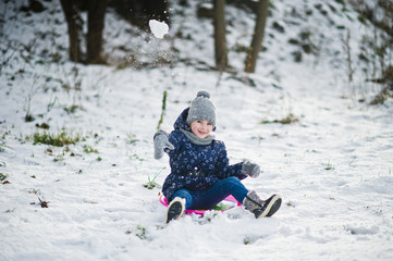 Cute little girl with saucer sleds outdoors on winter day.