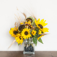 Autumn sunflowers in a glass vase on a wooden table