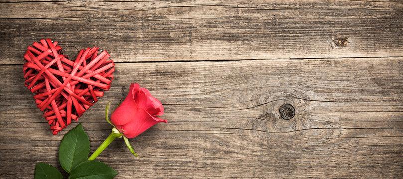 Red wicker heart and rose flower on wooden background