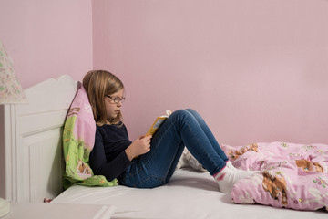 Obraz premium Mädchen liest auf ihrem Bett 