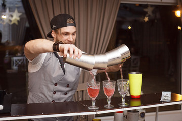 The barman pours an alcoholic cocktail at the bar