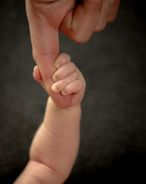 Baby is holding fingers of his father - happy family moments of parents with their children