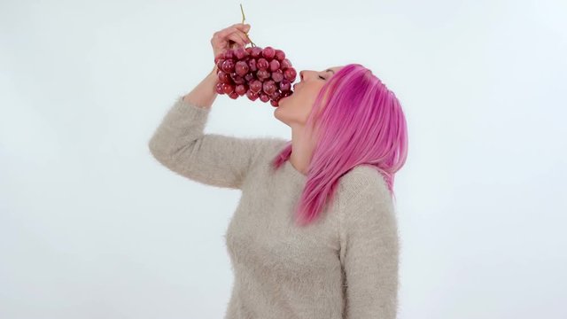 A young woman is eating grapes from the bottom.