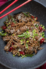 Above view of stir-fried beef meat with soba noodles, vertical shot, close-up