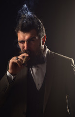 Man with beard holds cigar on grey background