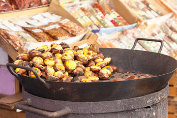 Autumn chestnuts roasting over an old charcoal burner in a street market stall