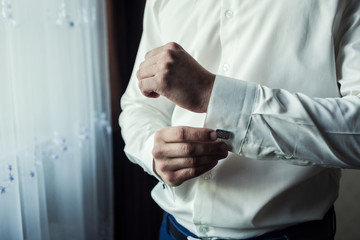 businessman dresses white shirt, male hands closeup,groom getting ready in the morning before wedding ceremony