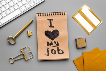 Find dream job. Handwritten motto I love my job in notebook near stationery on grey background top view