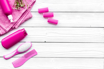 Hair washing and styling tools. Comb, shampoo, hairspray, curlers on white wooden background top view copyspace