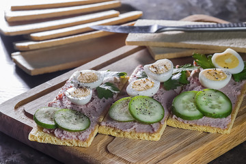Fresh homemade meat pate on over crispbread on wooden board.
