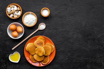 Make fluffy pancakes. Ingredients, cakes and toppings like nuts and honey on black background top view copyspace