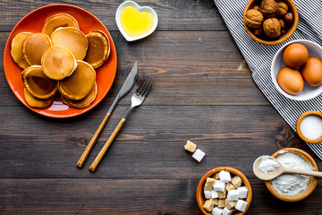 Make fluffy pancakes. Ingredients, cakes and toppings like nuts and honey on dark wooden background top view