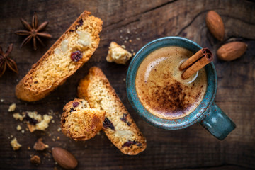 Cup of espresso coffee with a stick of cinnamon as a spoon and homemade slices of Italian cantuccini biscuits for breakfast