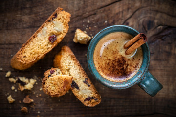Cup of espresso coffee with a stick of cinnamon as a spoon and homemade slices of Italian cantuccini biscuits for breakfast